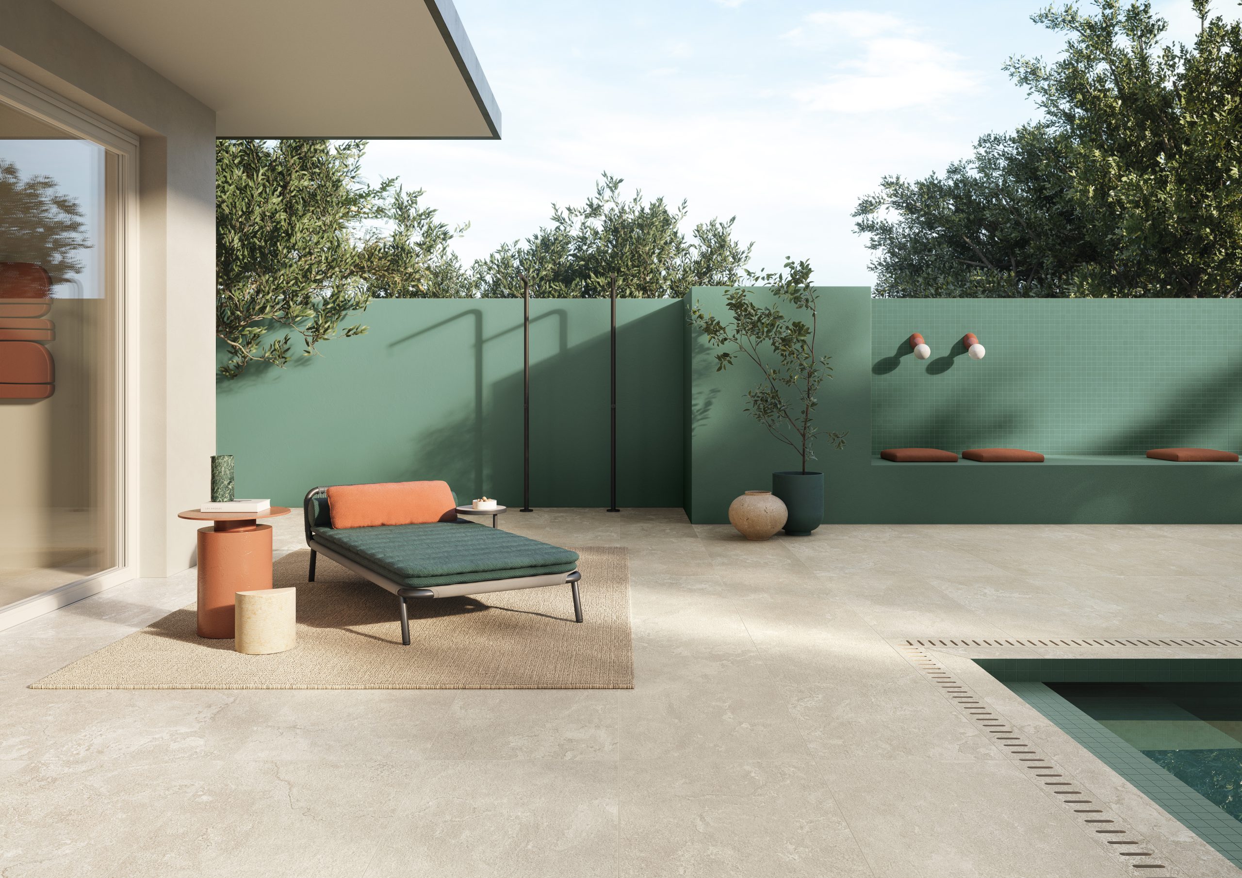 Ljust beige terrassgolv med grön vägg, träd och poolkant